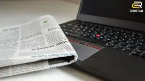 Laptop with newspaper on top of it.