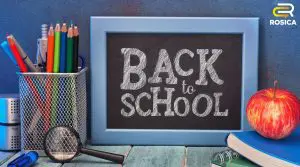 Chalkboard with text saying Back to School. On the left is a cup of colored pencils. On the right is an apple.
