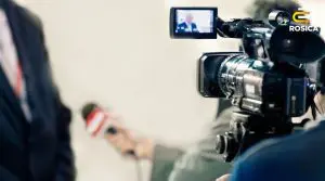 Camera with reporter holding microphone.
