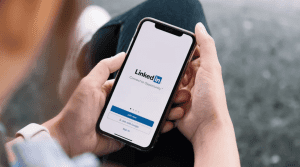 Man holding phone with the LinkedIn app open.