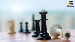 Black king in focus on a chessboard, with a toppled white king nearby and blurred pieces in the background; ROSICA logo in the top-right corner.