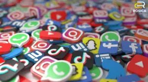 Pile of colorful social media icons scattered across a surface, with a Rosica logo in the top-right corner.