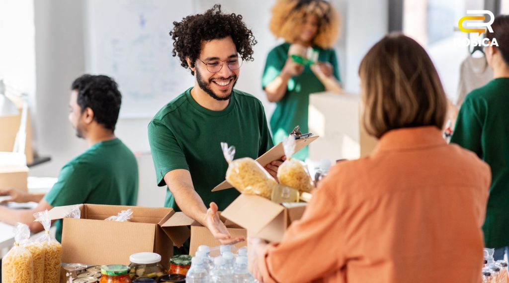 Two people exchanging a box with bread over a table.